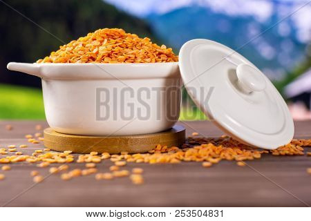 Lot Of Whole Raw Red Lentils In A Ceramic Stewpan With Country Nature In Background