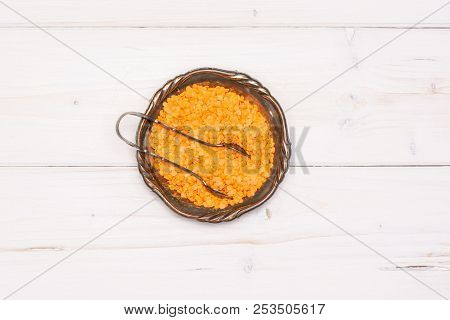 Lot Of Whole Raw Red Lentils With Tongs In Old Iron Bowl Flatlay On Grey Wood