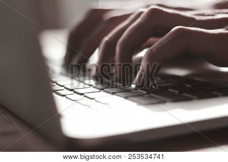 Blurred Image Of Male Hand Typing On Laptop Keyboard.close Up