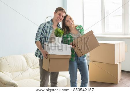 Home, People, Moving And Real Estate Concept - Happy Couple Having Fun And Riding In Cardboard Boxes