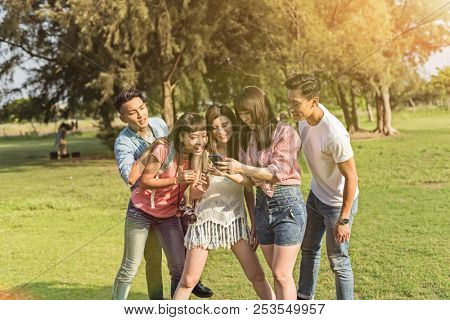 Asian people look something at cellphone with his friends in the park