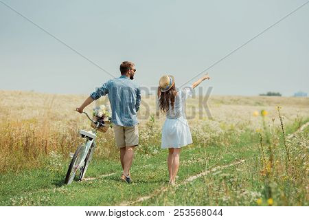 Back View Of Couple With Retro Bicycle In Summer Field With Wild Flowers