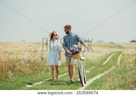 Smiling Couple In Sunglasses With Retro Bicycle In Summer Field With Wild Flowers