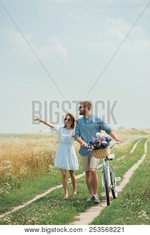 Smiling Couple In Sunglasses With Retro Bicycle In Summer Field With Wild Flowers