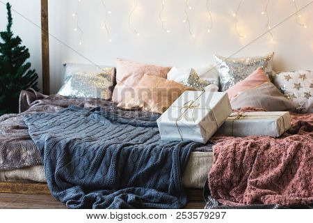 Xmas In Morning Bedroom. Double Bed In Christmas Interior On White Wall Background With Cozy Lights.