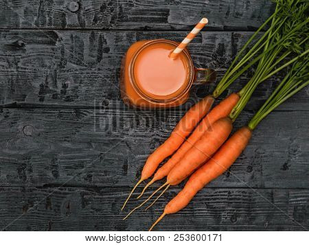 A Open Mug Of Carrot Smoothie And A Bunch Of Carrots On A Rustic Table. The View From The Top. Flat 