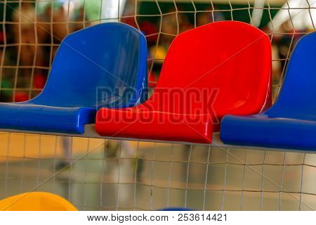 Multicolored Empty Plastic Chairs In The Stands Of The Stadium. Many Empty Seats For Spectators In T