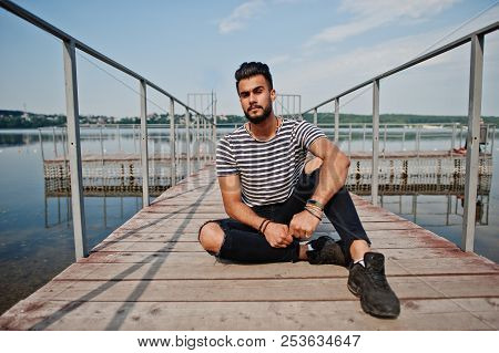 Handsome Tall Arabian Beard Man Model At Stripped Shirt Posed Outdoor On Pier Of Lake. Fashionable A