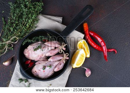 Small Raw Quals With Some Spice Ready For Cooking On Black Round Pan .