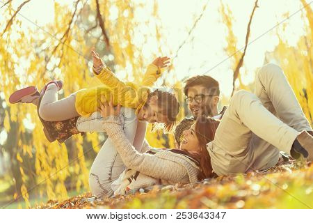 Young Family Enjoying A Beautiful Autumn Day In Nature, Having A Picnic And Spending Time Together; 
