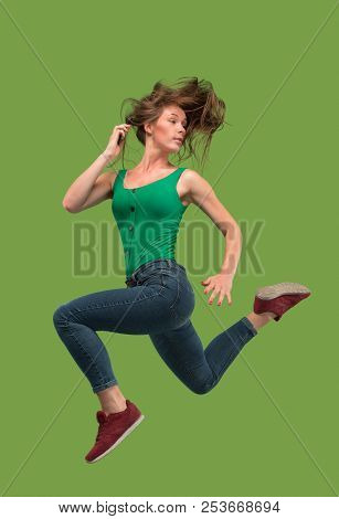 Freedom In Moving. Mid-air Shot Of Pretty Happy Young Woman Jumping And Gesturing Against Orange Stu