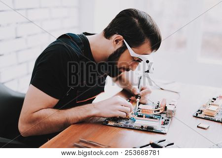 Young Bearded Man Repairing Motherboard From Pc. Repair Shop. Worker With Tools. Computer Hardware. 