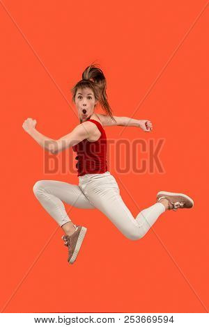 Freedom In Moving. Mid-air Shot Of Pretty Happy Young Woman Jumping And Gesturing Against Orange Stu