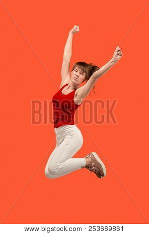 Freedom In Moving. Mid-air Shot Of Pretty Happy Young Woman Jumping And Gesturing Against Orange Stu