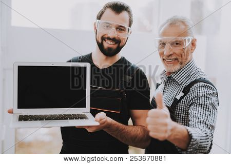 Two Smiling Men With Laptop In Workshop In Repair Shop. Thumbs Up. Computer Hardware. Young And Old 