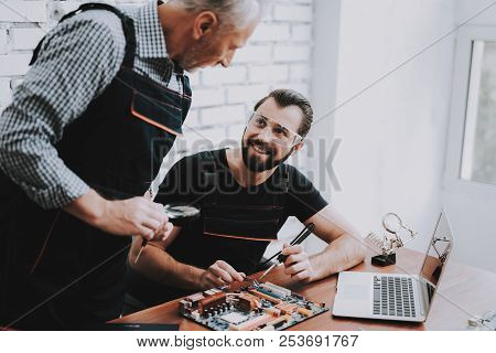 Two Men Repairing Hardware Equipment In Workshop. Repair Shop. Worker With Tools. Computer Hardware.