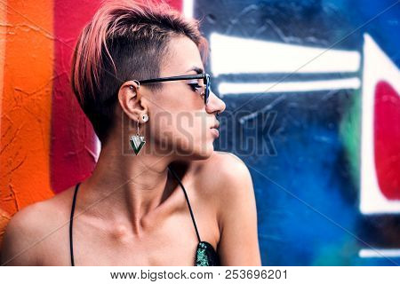 Street Punk Or Stylish Girl With Pink Dyed Hair. Woman With Piercing In Nose, Ears Tunnels And Unusu
