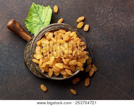 Heap Of Yellow Raisins. Top View Of Dried Grapes With Green Leaf.