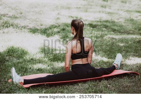 Young Sporty Woman Doing A Leg Split In Park. Toned Picture