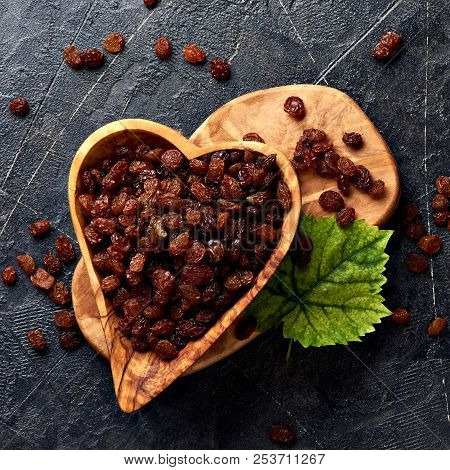 Brown Raisins In Bowl And Green Leaf. Top View Of Dried Grapes.