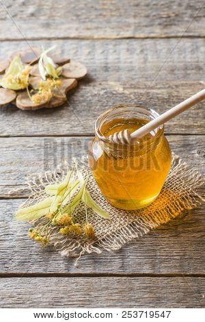 Glass Jar Of Honey, Linden Flowers On Wooden Background.
