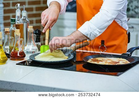Kitchen Preparation: The Chef Fries Fresh Pancakes In Two Pans
