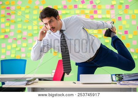 Man in the office with many conflicting priorities doing exercis