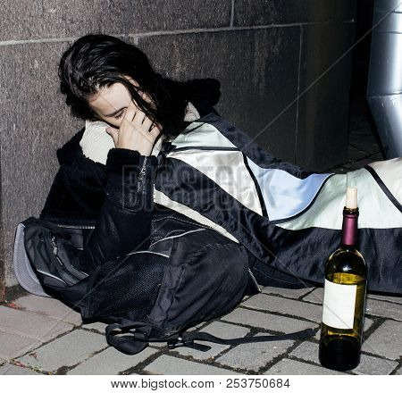 Young Poor Ttenage Girl Sitting At Dirty Wall On Floor With Bott