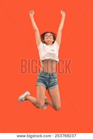 Freedom In Moving. Mid-air Shot Of Pretty Happy Young Woman Jumping And Gesturing Against Orange Stu