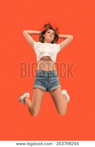 Freedom In Moving. Mid-air Shot Of Pretty Happy Young Woman Jumping And Gesturing Against Orange Stu