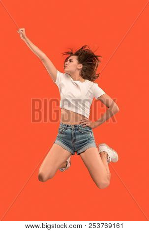 Freedom In Moving. Mid-air Shot Of Pretty Happy Young Woman Jumping And Gesturing Against Orange Stu