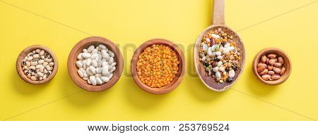 Assortment Of Legumes In Wooden Bowls On Yellow, Background, Isolated, Top View, Banner.