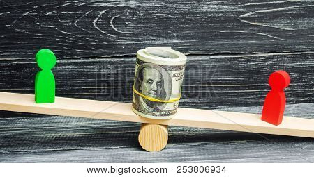 Wooden Figures Of People On Scales And Dollars Between Them. A Dispute Between Two Businessmen. Tria