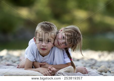 Two Young Happy Cute Blond Smiling Children, Boy And Girl, Brother And Sister Laying Embraced On Peb