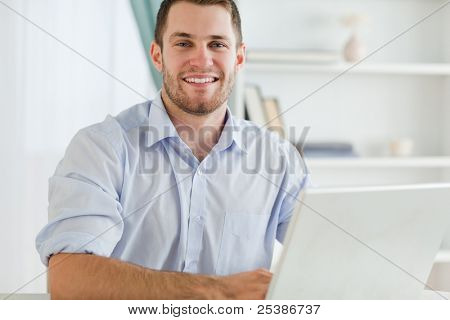 Smiling young businessman with rolled up sleeves in his home business