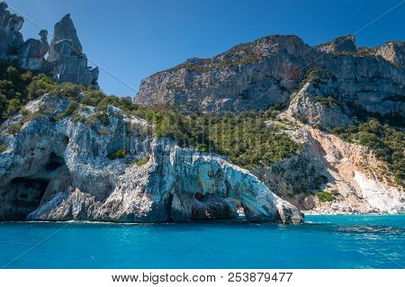People Jumping Into The Water At Famous Cala Goloritze Beach On The Italian Island Of Sardinia