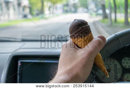 The Driver Holds The Ice Cream While Driving A Car
