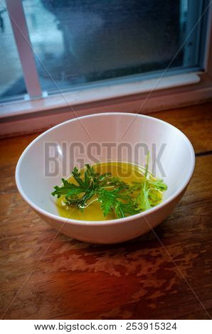 A Citronella Plant Leaf Resting In Oil To Make Homemade Mosquito Repellant