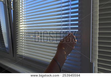 The Woman's Hand Opens The Horizontal Blinds On The Windows.