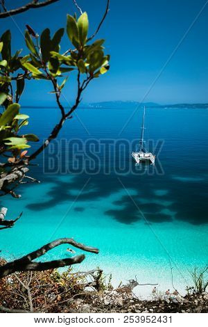 White Catamaran Yacht At Anchor On Clear Azure Surface With Dark Pattern In Calm Blue Lagoon. Unreco