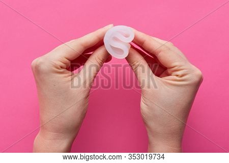 Horizontal Picture Of Unknown Hands Holding Rubber Menstrual Cup In Both Hands, Twisting It, Being R