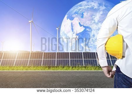 Industry Worker Or Engineer Working With Solar Panels With Wind Turbines Against Mountanis Landscape