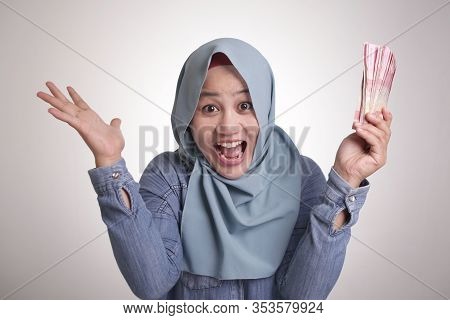 Portrait Of Indonesian Muslim Woman Holding Rupiah Money, Smiling Laughing Winning Gesture