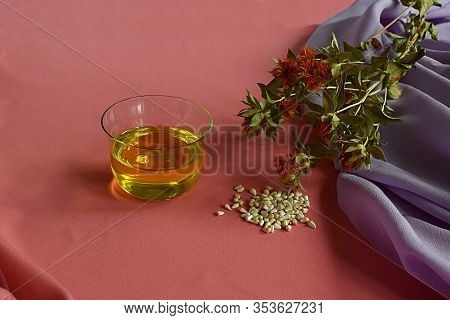 Safflower. Safflower Oil, Seeds And Stems With Flowers On A Pink Background.