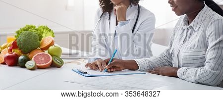 Cropped Of Black Woman Dietologist Consultating Female Patient At Privat Clinic, Patient Filling For