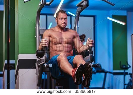 Powerful Athletic Bodybuilder Doing Excersise On A Parallel Bars, Pumping His Abs And Lifting His Le