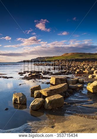 Kimmeridge Sunshine Illuminating Golden Rocks On The Shoreline