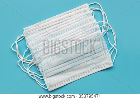 Several Surgical Ear-loop Masks Lying On Blue Background. Top View. Protection Concept