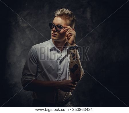 Young, Hipster Looking, Adult Student Guy In A White Shirt With Tattoos On His Hand Posing In A Dark