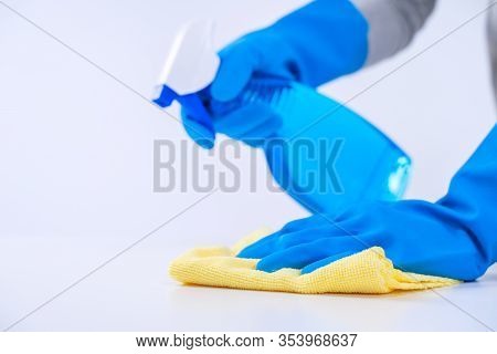 Young Woman Housekeeper Is Doing Cleaning White Table In Apron With Blue Gloves, Spray Cleaner, Wet